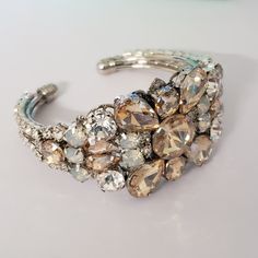 This listing is for the bracelet only Beautiful Bridal Bracelet Art Deco style . Made with clear crystals , white opal, and gold shadow stones set in rhodium plated metal. This bracelet is about 1 1/4 inches wide This is an open bangle so it will fit any wrist size. Matching hair comb at this link: https://www.etsy.com/listing/708567420/gold-shadow-crystal-hair-combwhite-opal?ref=shop_home_active_1 Please contact me if you have any questions. Hand crafted with Love. Glamorous Adjustable Bangle Bracelets, Adjustable Crystal Cuff Bangle Bracelet, Adjustable Crystal Cuff Bracelet In Bangle Shape, Wedding Jewelry Bangle With Jewels, Adjustable Jeweled Cuff Bracelet For Formal Events, Adjustable Jeweled Cuff Bracelet For Formal Occasions, Formal Adjustable Jeweled Cuff Bracelet, Elegant Cuff Jewelry For Weddings, Adjustable Hand Set Silver Cuff Bracelet