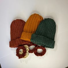 three knitted hats and mittens laid out on top of a white countertop