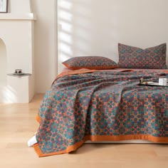 the bed is made up with an orange and blue comforter on top of it