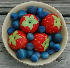 a bowl filled with blueberries and strawberries on top of a wooden table next to other fruit