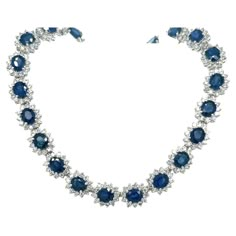 Introducing a circle link 18k white gold choker necklace with natural Blue Sapphires and diamonds. 40 individual links each containing a vivid no heat Blue Sapphire. The Sapphires are oval cut, totaling approximately 36.0 carats total and measuring 6x5 mm. 4-prong set Blue Sapphire with 12 round cut diamonds forming a halo in a shared prong mounting. 480 diamonds totaling approximately 9.60 carats total. Diamonds are H-I color, SI1-SI2 Clarity. Necklace set in 18k white gold, measuring 17 inches Luxury Blue Diamond Cut Necklace, Luxury Sapphire Necklace With Halo Setting, Luxury Blue Sapphire Necklace, Luxury Oval Sapphire Necklace, Luxury Sapphire Diamond Necklace With Accents, Sapphire Choker, Black Tweed, Star Sapphire, Gold Choker Necklace