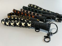 four black and white crocheted key chains with metal hooks on each one side