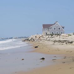 a house on the beach with waves coming in from the water and sand around it