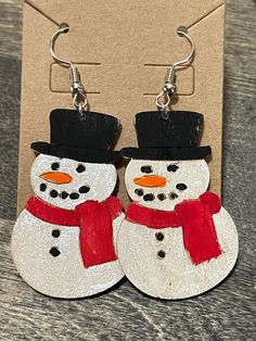 two snowmen wearing hats and scarfs on wooden earrings