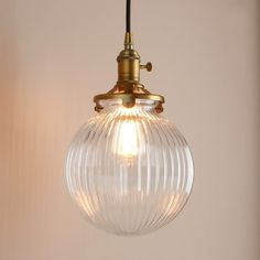 a light hanging from a ceiling with a glass ball on the bottom and a black cord attached to it