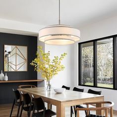 a dining room table with black chairs and a white chandelier hanging from the ceiling