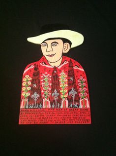 a man wearing a cowboy hat and red sweater with trees on the chest is standing in front of a black background