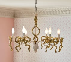 a chandelier hanging from the ceiling in a room with pink walls and wallpaper