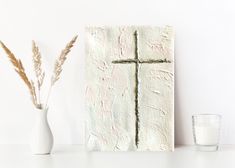 a cross painted on the side of a wall next to a vase