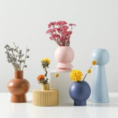 four different vases with flowers in them on a white countertop next to each other