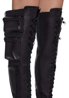 These thigh high combat boots have a vegan leather construction, heeled platform soles, zippered pockets on the sides, buckle strap details, adjustable lace-ups, and side zip closures. Black Knee High Combat Boots, Black High Top Air Force 1, Edgy Knee-high Heeled Boots For Streetwear, Edgy Faux Leather Knee-high Boots, Edgy Knee-high Platform Combat Boots, Gothic Black Knee-high Boots For Streetwear, Black Gothic Knee-high Boots For Streetwear, Edgy Knee-high Boots For Streetwear, Black Punk Platform Boots With Zipper Closure