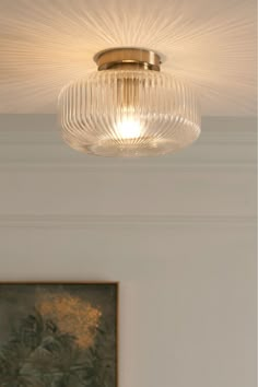 a close up of a ceiling light with a painting on the wall in the background