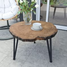 a coffee table made out of a tree stump with a cup on it and flowers in a vase