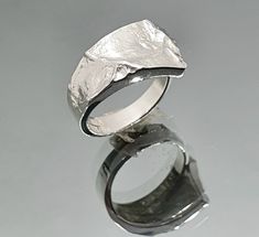 "Sea of Storms series was designed by the renowned Finnish goldsmith and jewelry artist Matti Hyvärinen in the 1960's inspired by the first lunar landings. Sea of Storms - Mare Procellarum is the biggest lunar \"sea\". This ring was made in 1974 in Matti's workshop in Turku, Finland. It is from our old stock - vintage, but never used. The size is adjustable so it fits most sizes. Material: 925 Sterling silver Measurements: width 12 mm on the front, 4 mm on the back Hallmarked: MJH, 925, Turku ci Hand Cast Modernist Jewelry For Gifts, Modernist Hand Cast Jewelry As Gift, Modernist Hand-cast Jewelry For Gifts, Modern Hand Cast Jewelry As Gift, Contemporary White Gold Rings For Gift, Contemporary Rings With Unique Design For Gift, Hand Cast Modernist Ring, Hand Cast Modernist Ring As Gift, Modernist Hand Cast Ring As Gift