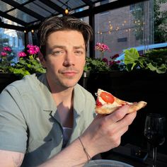 a man sitting at a table with a slice of pizza in front of his face