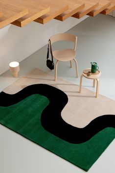 a room with a rug, chair and table on the floor in front of stairs