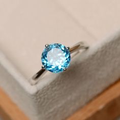 a ring with a blue topaz sits in a box