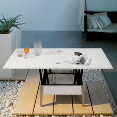 a white table sitting on top of a wooden floor next to a planter filled with succulents