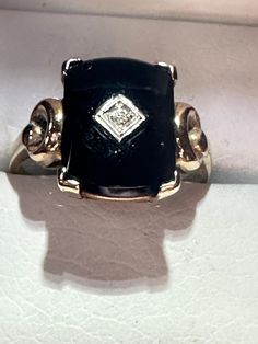 "For your consideration is a vintage yellow gold black onyx signet ring with a center accent diamond. This gorgeous pieces is 10K and hallmarked as such. It also has a makers mark of what looks to be \"B&F\".  The black onyx stone measures 14mm x 10mm. The center has a white gold diamond shape with a 1-point diamond in the middle.  The sides are done in art deco styling with circles on each side.  It is a size 8 and weighs in at 3.22 grams.  It's a great opportunity to own a piece of history!" Antique Black Signet Ring Collectible, Classic Black Diamond Ring Stamped 14k, Formal Black Diamond Ring Stamped 14k, Vintage Black Signet Ring With Gemstone, Classic Hallmarked Black Diamond Ring, Classic Black Hallmarked Diamond Ring, Vintage Onyx Signet Ring For Anniversary, Vintage Black Onyx Signet Ring, Vintage Black Gemstone Signet Ring