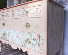 an old dresser is painted in pink and gold with floral designs on the drawers,