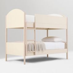 a white bunk bed sitting next to a pillow on top of a wooden frame and mattress