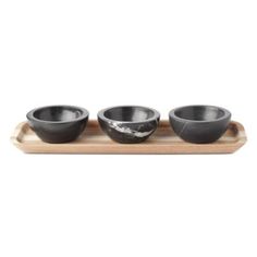 three black bowls sitting on top of a wooden tray