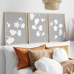 two framed art prints on the wall above a bed with pillows and throw pillows in front of it