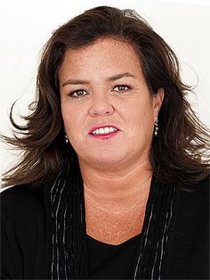 a woman with long hair wearing a black shirt and necklace, looking at the camera