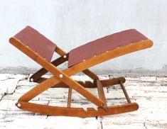 a wooden rocking chair sitting on top of a white brick floor next to a wall