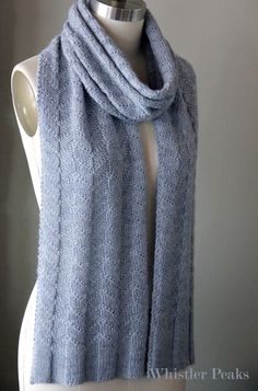 a white mannequin wearing a blue knitted scarf