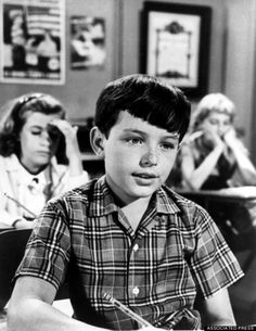 an old black and white photo of a young boy sitting at a desk