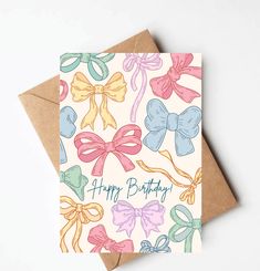 a card with bows on it and the words happy birthday written in blue, pink, yellow and green