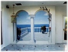 an open door leading to a balcony overlooking the ocean with flowers on it and a birdcage