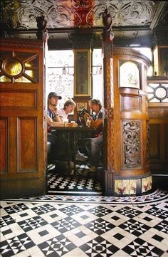 three people sitting at a table in a room with black and white checkered flooring