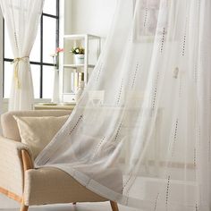 a living room with white curtains and a chair