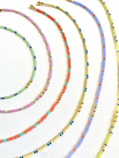 several different colored beads are arranged on a white surface, including one beaded necklace