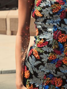 a woman in a floral print dress is holding her hand on her hip while walking down the street