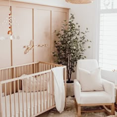 a baby's room with a crib, rocking chair and potted plant