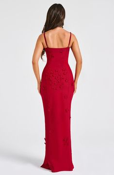 a woman wearing a red dress with cut out details on the side and back, looking down