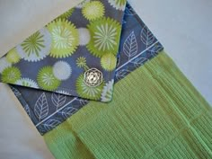 a green and blue cloth with a button on it sitting next to a piece of fabric