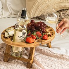 a tray with wine, cheese and strawberries on a bed next to a glass of wine