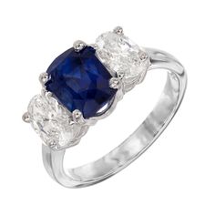 Velvety, rich blue sapphire and diamond engagement ring. Spectacular 2.79ct cushion cut center sapphire, mounted in a platinum three-stone setting. The sapphire is accented by 2 sparkly oval cut diamonds totaling 1.20cts. The sapphire is GIA Certified natural, with simple heat. Designed and crafted in the Peter Suchy Workshop. 1 cushion cut blue sapphire, MI approx. 2.79cts GIA Certificate # 2235213947 2 oval diamonds, H VS approx. 1.20cts Size 6.75 and sizable Platinum Stamped: Plat 7.2 grams W Blue Radiant Cut Three-stone Ring, Three Stone Sapphire Ring With Radiant Cut Diamond, Luxury Sapphire Cushion Cut Ring, Blue Three-stone Cushion-cut Jewelry, Three Stone Radiant Cut Sapphire Ring, Blue Three-stone Cushion Cut Jewelry, Blue Three Stone Cushion Cut Jewelry, Luxury Three Stone Asscher Cut Sapphire Ring, Luxury Three-stone Asscher Cut Sapphire Ring