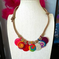 a white mannequin holding a multicolored necklace on it's neck