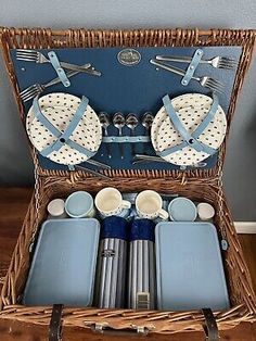 a wicker picnic basket filled with blue and white dishes