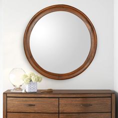 a round mirror on the wall above a dresser