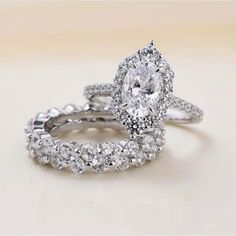 two wedding rings with diamonds on top and one diamond in the middle, sitting next to each other