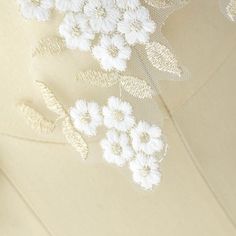 white flowers are on the side of a piece of fabric