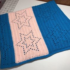 a blue and pink crocheted blanket sitting on top of a white countertop