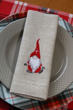 a napkin with an image of a gnome on it is sitting on a plaid table cloth