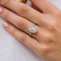 a woman's hand with a diamond ring on top of her finger and the other hand holding an engagement ring